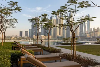 a row of benches in a park with a city skyline at Lux 1BR Beachfront Living Palace Beach Residence in Dubai