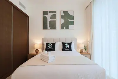 a bedroom with a large white bed with two lamps at Lux 1BR Beachfront Living Palace Beach Residence in Dubai