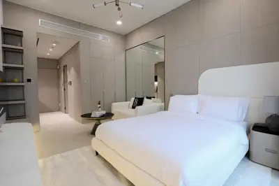a bedroom with a large white bed and a living room at Gracious Studio in Pearl House by Imtiaz in Dubai