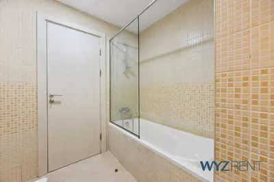 a bathroom with a tub and a glass shower door at Salt & Sand Hamptons Glow 2BR Sulafa Tower in Dubai