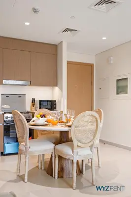 a kitchen with a table and chairs with wine glasses on it at Tranquil Boho 1BR in Surf 2 Creek Beach Access in Dubai