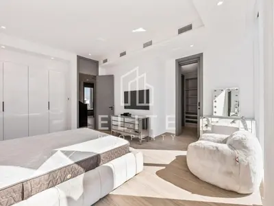 a white bedroom with a large bed and a chair at Luxury Ixora Family Villa in Dubai