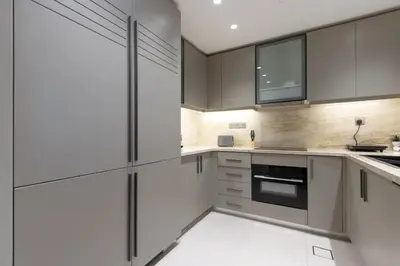a kitchen with white cabinets and black appliances at Newly Upgraded 2BR - Steps from Burj Khalifa and Opera in Dubai
