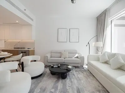 a living room with white furniture and a kitchen at La Vie Seaside with Beach Access in Dubai