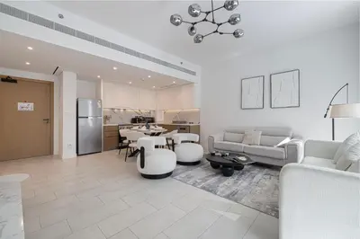a living room with white furniture and a kitchen at La Vie Seaside with Beach Access in Dubai