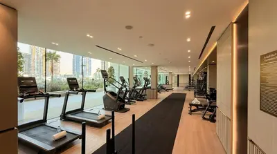 a gym with cardio equipment and a large window at Binghatti Phoenix! Longest Pool in Dubai! Brand New Building, 2 Double Beds! in Dubai