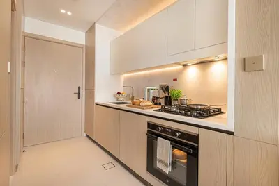 a kitchen with a stove top oven next to a door at Binghatti Phoenix! Longest Pool in Dubai! Brand New Building, 2 Double Beds! in Dubai
