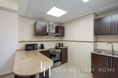 a kitchen with brown cabinets and a counter top at LUX The JLT Gold Crest Suite in Dubai