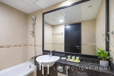 a bathroom with a sink and a tub and a mirror at LUX The JLT Gold Crest Suite in Dubai