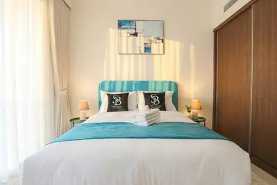 a bedroom with a large bed with a blue headboard at Lux 2BR Beachfront Escape Palace Beach Residence in Dubai