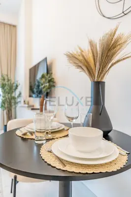 a dining room table with plates and glasses on it at Just Minutes Drive From Dubai Autodrome, Conveniently Located Within A Short Walk Of The Bus Stop, Azizi Vista, Dubai Studio City by Deluxe Holiday Homes in Dubai