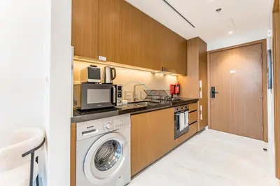 a kitchen with a washing machine and a microwave at Just Minutes Drive From Dubai Autodrome, Conveniently Located Within A Short Walk Of The Bus Stop, Azizi Vista, Dubai Studio City by Deluxe Holiday Homes in Dubai