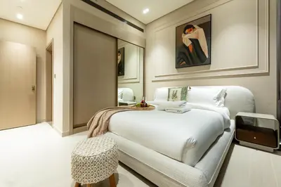 a bedroom with a white bed and a stool at Luxury Apartment in JVC with Private Balcony Pool in Dubai