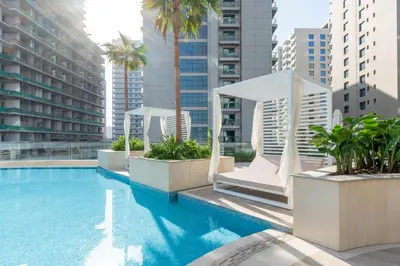 a large swimming pool with palm trees and buildings at Luxury Apartment in JVC with Private Balcony Pool in Dubai