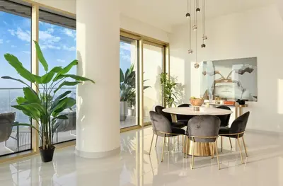 a dining room with a table and chairs and large windows at BLVD Beachfront Living with Skyline View in Dubai