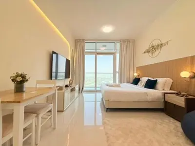 a bedroom with a bed and a desk and a television at Mahenti - Stunning Golf View Studio in Damac Hills in Dubai