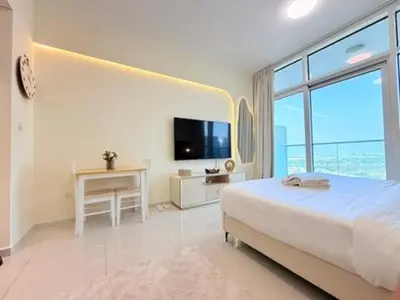 a white bedroom with a bed and a television at Mahenti - Stunning Golf View Studio in Damac Hills in Dubai