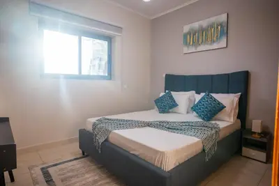 a bedroom with a bed with blue pillows and a window at Luxury 2BR Haven with Panoramic Scenery in Dubai