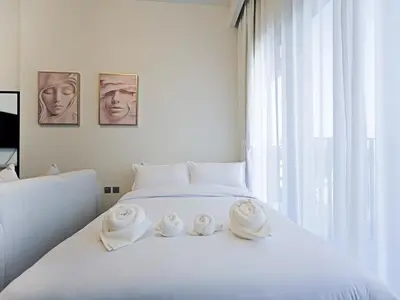 a white bed with three white towels on it at Elegant Modern Studio- Peaceful Studio City in Dubai