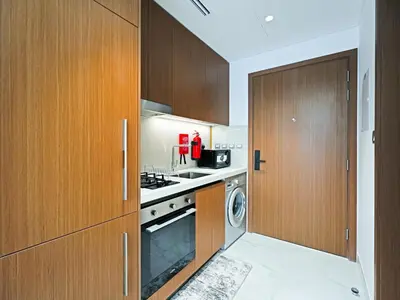 a kitchen with wooden cabinets and a washer and dryer at Elegant Modern Studio- Peaceful Studio City in Dubai