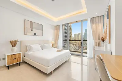 a white bedroom with a bed and a table at FIRST CLASS 1BR Burj Views , Prime Location in Dubai