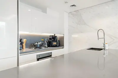 a white kitchen with a stove and a sink at FIRST CLASS 1BR Burj Views , Prime Location in Dubai