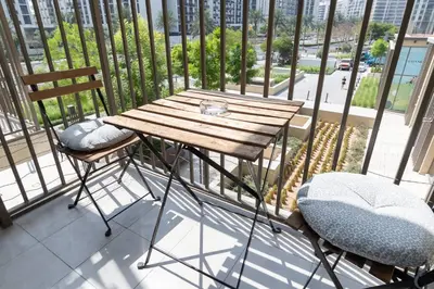 a wooden table and two chairs on a balcony at StayShort - Modern Dubai Hills Apartment Great Pool Sleeps 4 in Dubai