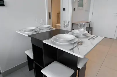 a table with plates and glasses on top of it at StayShort - Modern Dubai Hills Apartment Great Pool Sleeps 4 in Dubai
