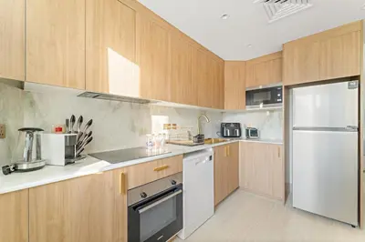 a kitchen with wooden cabinets and a stainless steel refrigerator at FIRST CLASS 2BR Burj View , Walk to Dubai Mall in Dubai