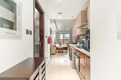 a kitchen with white walls and wooden cabinets at FIRST CLASS Studio Iconic Burj Khalifa View in Dubai