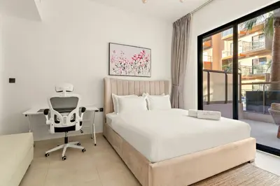 a bedroom with a bed and a desk and a chair at FIRST CLASS 1BR Tranquil Pool View Retreat in Dubai