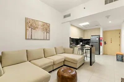 a living room with a couch and a kitchen at FIRST CLASS 1BR Tranquil Pool View Retreat in Dubai