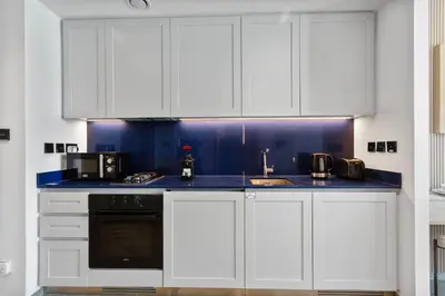 a kitchen with white cabinets and a blue counter top at Upscale Studio with Peninsula Lifestyle in Dubai