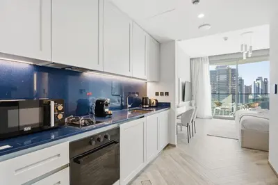 a kitchen with white cabinets and a view of a city at Upscale Studio with Peninsula Lifestyle in Dubai