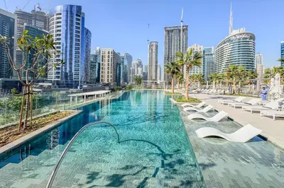 a swimming pool with a city skyline in the background at Upscale Studio with Peninsula Lifestyle in Dubai
