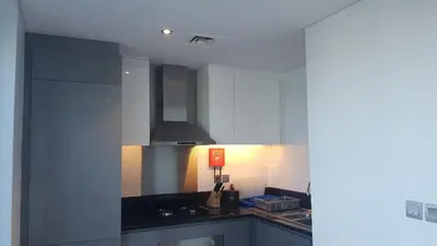 a kitchen with white cabinets and a black counter top at Exquisite Studio - Damac Prive with balcony & canal view in Dubai