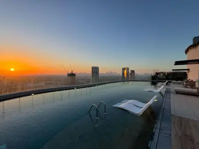 a swimming pool on top of a building with a sunset at Chic 2Bedroom with Exceptional Facilities in JVC in Dubai