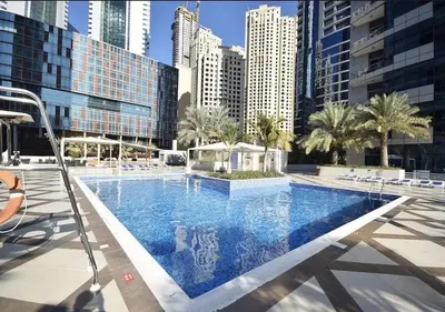 a large swimming pool in a city with tall buildings at Modern 1BR Marina 3mins walk to JBR Beach & Tram in Dubai