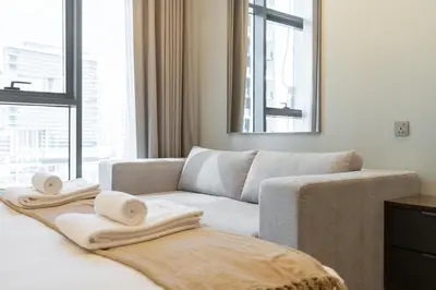 a living room with a couch and towels on a bed at Luxury 1BR in Nobles Tower - Business Bay Skyline in Dubai