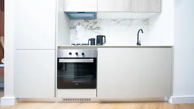 a white kitchen with a stove and a sink at Luxurious Cozy Studio with Balcony Pool & Gym in Dubai