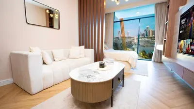 a living room with a white couch and a large window at Luxurious Cozy Studio with Balcony Pool & Gym in Dubai