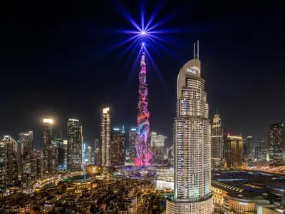a lit up city at night with a star on top at Luxury 2BHK with view of Burj Khalifa & Fountain in Dubai