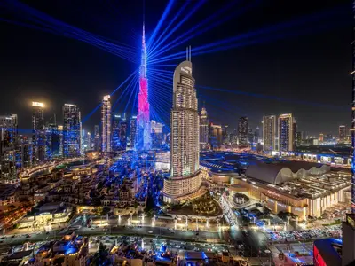 a city lit up at night with blue and red lights at Luxury 2BHK with view of Burj Khalifa & Fountain in Dubai