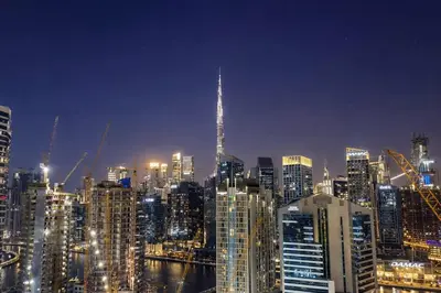 a nighttime view of a large city at night at Rentico l Luxury 1BR with Burj Khalifa & Canal View in Dubai
