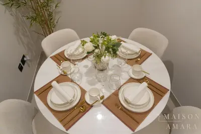 a white table with white plates and a vase of flowers at Modern Luxury Studio Damac Hills With Golf View in Dubai