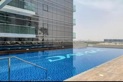 a large building with a swimming pool in front of it at Modern Luxury Studio Damac Hills With Golf View in Dubai
