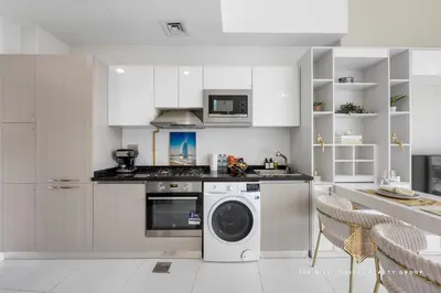 a kitchen with a washing machine and a microwave at Elegant Studio with Resort Amenities at Miraclez in Dubai