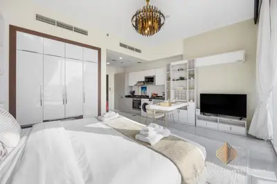 a white living room with a large bed and a tv at Elegant Studio with Resort Amenities at Miraclez in Dubai