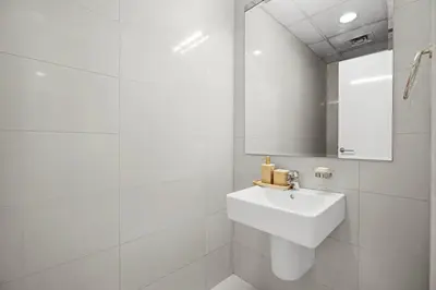 a white bathroom with a sink and a mirror at Elegant 1BR near downtown w Gym Tennis Basketball Courts in Dubai