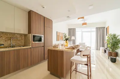 a kitchen with wooden cabinets and a bar with stools at Downtown Dubai - Near Burj Khalifa & DWTC-Gulfood - Imperial Avenue in Dubai
